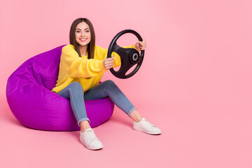 Full body profile side photo of young girl sit violet beanbag ride auto race weekend isolated over pink color background