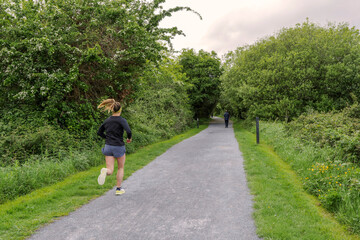 Female running in a park, Sport and fitness concept. Woman jogging on a small pathway.