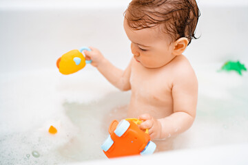 Little cute baby take a bath and playing with foam bubbles and toy