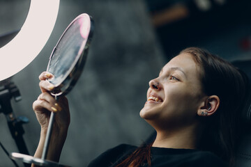 Young woman enjoying piercing nose ring watching mirror with smile