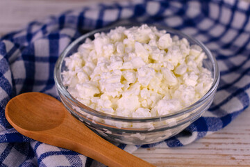 Cottage cheese in a bowl on a white wooden background.Close-up.
