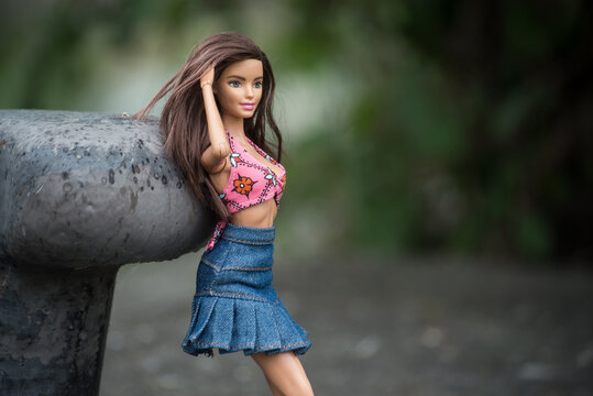 Mulhouse - France - 1 June 2022 - Portrait of brunette barbie doll wearing a blue jeans skirt and pink bra of bikini standing in border river