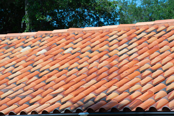 Overlapping rows of yellow ceramic roofing tiles covering residential building roof