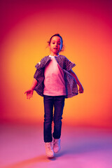 Funny little girl, kid wearing warm plaid shirt having fun isolated on yellow red background in neon. Concept of children emotions, fashion, beauty, school and ad concept