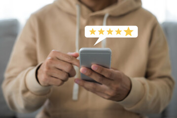 Customer hand pressing on smartphone screen with choose five star rating feedback icon and press...