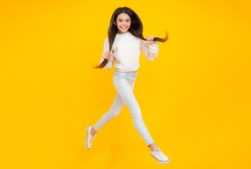 Fototapeta na wymiar Happiness, freedom, motion and child. Young teenager girl jumping in air over yellow background.