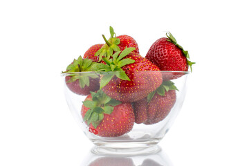 Several berries of ripe organic strawberries in a glass dish, close-up, isolated on a white background.