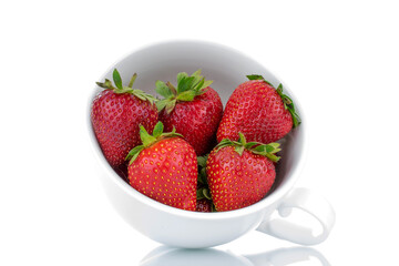 Several berries of ripe organic strawberries in a white ceramic cup, close-up, isolated on a white background.