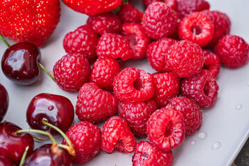 A plate of summer fruit. A close-up of raspberries on a plate.
