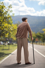 Elderly man standing with a cane on an asphalt pedestrian track