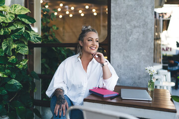 Cheerful Caucasian woman in white shirt smiling during time for doing distance job in terrace...