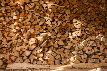 Firewood pile. Wooden wall from pile of firewood stacked in an old farm shed. Birch firewood are neatly stacked.