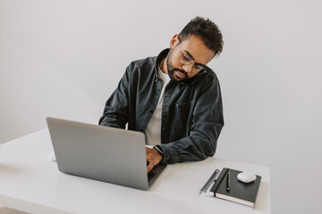 Cheerful Young African man with beard, eyeglasses is talking mobile, making note