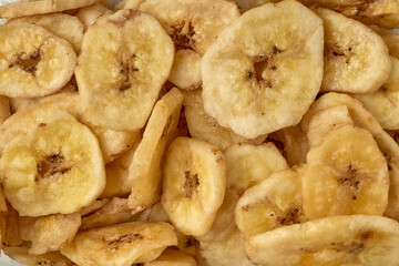Obraz na płótnie Canvas Banana chips background top view. Dried banana slices texture. Heap of dried bananas.