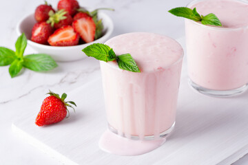 Yogurt , buttermilk or kefir with strawberry. Yogurt in glass on light background. Probiotic cold fermented dairy drink. Gut health, fermented products, healthy gut flora concept