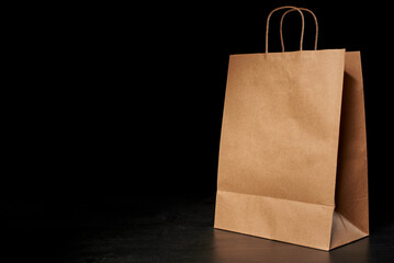 A brown paper bag on a black background at 45 degrees. Medium paper bag. Brown craft bag. Delivery...