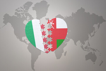 Fototapeta premium puzzle heart with the national flag of oman and italy on a world map background. Concept.