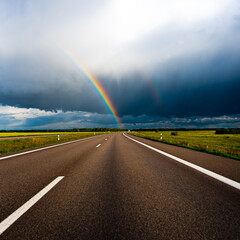 Rainbow on a dark sunny and rainy day over the highway; might be LGBT