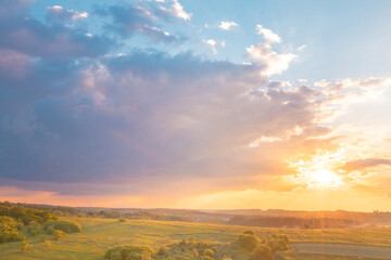 Stunning sunset sky with clouds over green hills. Summer countryside view.