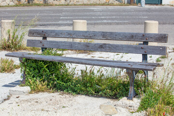 Vieux banc au bord de la route avec herbes sauvages