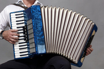 blue accordion, played by a man, in the frame only hands