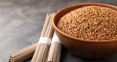 Buckwheat paste with buckwheat porridge on a black cement background. Raw noodles. Ingredients for a gluten-free dish. Dried buckwheat soba noodles.Traditional Japanese food.Health food.Copy space.