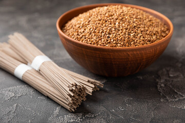 Buckwheat paste with buckwheat porridge on a black cement background. Raw noodles. Ingredients for a gluten-free dish. Dried buckwheat soba noodles.Traditional Japanese food.Health food.Copy space.