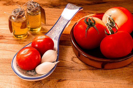 Receta t&iacute;pica Catalu&ntilde;a. Pan con tomate untado y aceite sobre encimera de madera y un bol con ajos. 