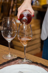 Woman pouring rose wine from a bottle into a glass
