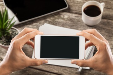 Human holding a smartphone with  screen on table. Office environment.