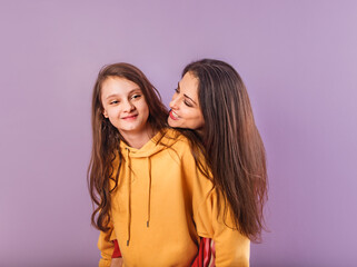 Happy smiling beautiful young healthy mother and cute daughter posing in fashion trendy hoodie...