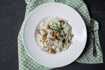Tasty mushroom risotto on black concrete table, top view. Delicious italian cuisine. 