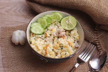 Pork Fried Rice, Chinese Style Fried Rice in a Bowl with Cucumber and Lemon Served on a brown wooden table.