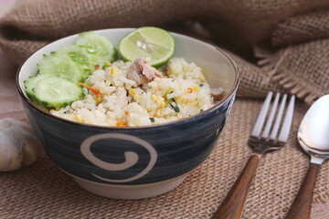 Pork Fried Rice, Chinese Style Fried Rice in a Bowl with Cucumber and Lemon Served on a brown wooden table.
