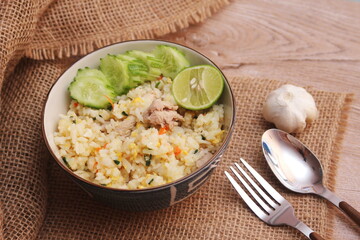 Pork Fried Rice, Chinese Style Fried Rice in a Bowl with Cucumber and Lemon Served on a brown wooden table.