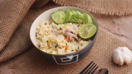 Pork Fried Rice, Chinese Style Fried Rice in a Bowl with Cucumber and Lemon Served on a brown wooden table.