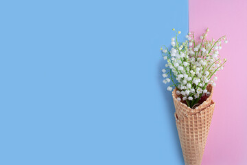 Bouquet of lilies of the valley on blue and pink background. Flat lay, top view, copy space. floral background with spring flowers.  Mother's day, Valentines Day, Birthday celebration concept