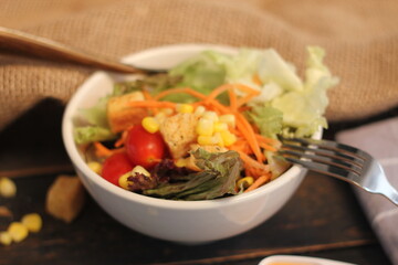 Caesar salad in white bowl served with Caesar dressing. on a black wooden table.