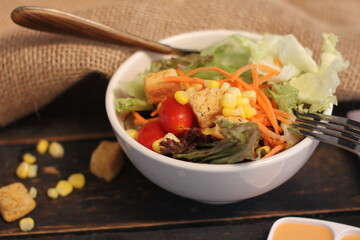 Caesar salad in white bowl served with Caesar dressing. on a black wooden table.