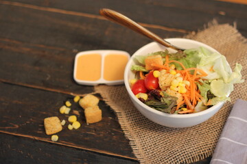 Caesar salad in white bowl served with Caesar dressing. on a black wooden table.