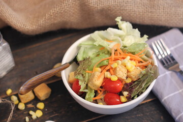 Caesar salad in white bowl served with Caesar dressing. on a black wooden table.