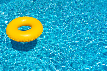Yellow ring floating in blue swimming pool. Inflatable ring, rest concept