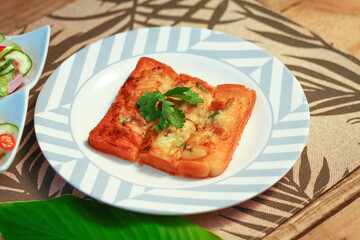 Fried bread with minced pork spread with cucumber dipping sauce on a wooden table.