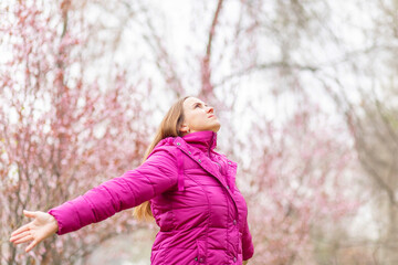 Relaxed woman wearing headphones breathing fresh air listening to music in a forest or park