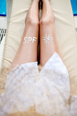 Closeup female leg with sun shape. Sun protection. Suncream, on her smooth tanned legs. Sunblock.