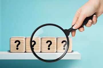 Magnifying glass on wood cubes with question marks,  test concept