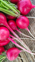 Ripe red radish lies on a wooden background.