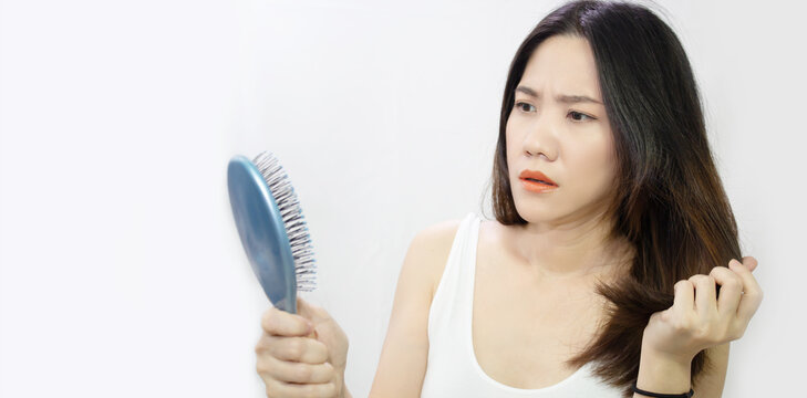 Asian woman are looking a her hair loss and holding blue comb and hair with worry face and shocked