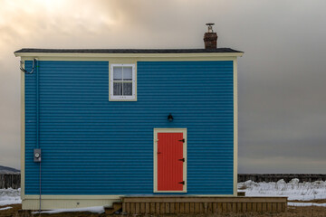 A vibrant blue clapboard siding exterior wall of a vintage two story house with a single double...