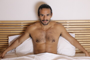 Attractive Hispanic man shirtless in bed